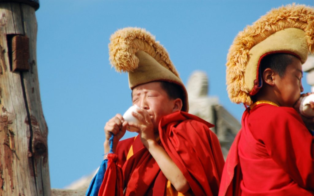 Young Mongolian Buddhist monks blowing conch-shell horns